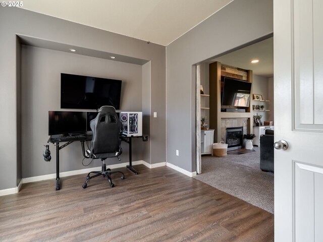 office area with wood finished floors, a tiled fireplace, baseboards, and recessed lighting