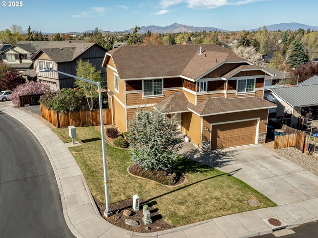 view of front of home with roof with shingles, concrete driveway, an attached garage, stone siding, and a mountain view