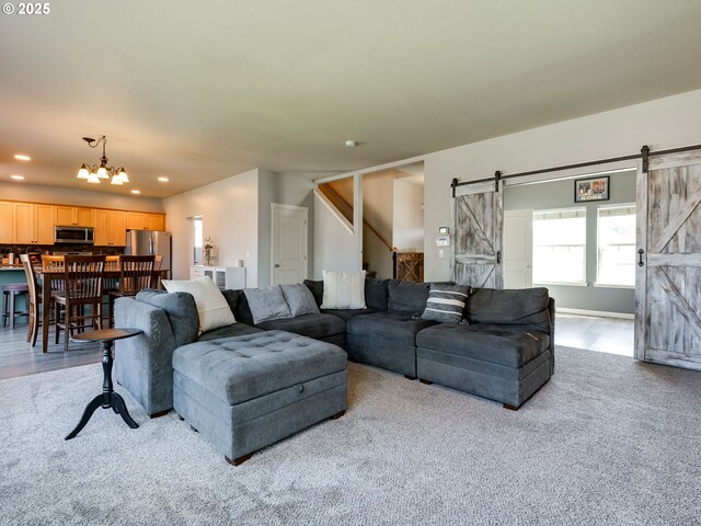 carpeted living room featuring a barn door, recessed lighting, a chandelier, and stairway
