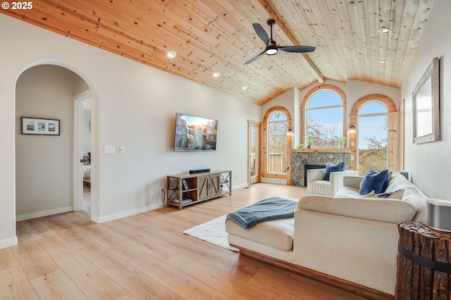 living area featuring high vaulted ceiling, light wood-style flooring, a ceiling fan, arched walkways, and wood ceiling