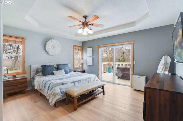 bedroom with multiple windows, a raised ceiling, and access to outside