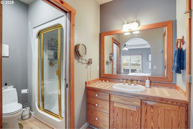 bathroom featuring toilet, a stall shower, vanity, and ceiling fan