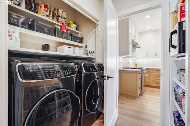 clothes washing area featuring light wood finished floors, recessed lighting, washing machine and dryer, and laundry area