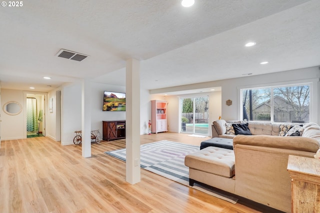 living area featuring visible vents, baseboards, light wood-type flooring, recessed lighting, and a textured ceiling