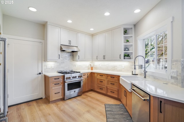 kitchen with open shelves, a sink, stainless steel appliances, light wood-style floors, and under cabinet range hood