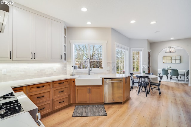 kitchen with light wood-style flooring, recessed lighting, a sink, decorative backsplash, and stainless steel dishwasher