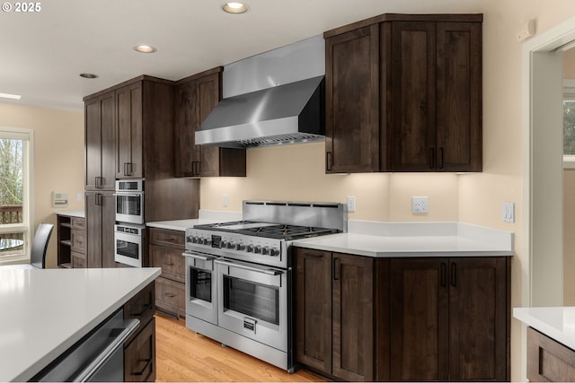 kitchen with wall chimney exhaust hood, light countertops, and stainless steel appliances