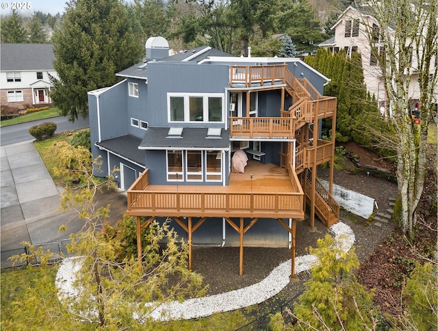 back of property featuring a garage, a shingled roof, and a wooden deck