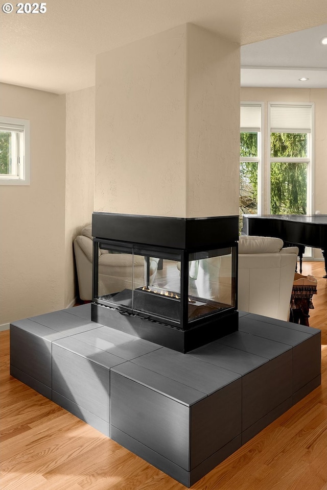 bedroom featuring recessed lighting, light wood-style flooring, and a multi sided fireplace