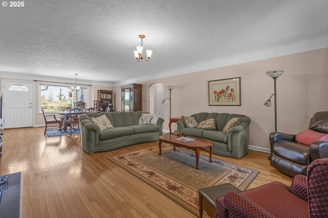 1910 Saginaw St S, Salem, OR 97302 - living room featuring a chandelier, light wood-style flooring, baseboards, a textured ceiling, and arched walkways