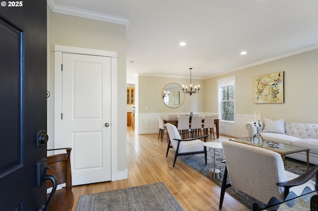 living room with light hardwood / wood-style floors, crown molding, and an inviting chandelier