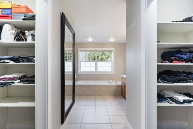 bathroom featuring vanity, tile patterned flooring, a relaxing tiled tub, and a textured ceiling