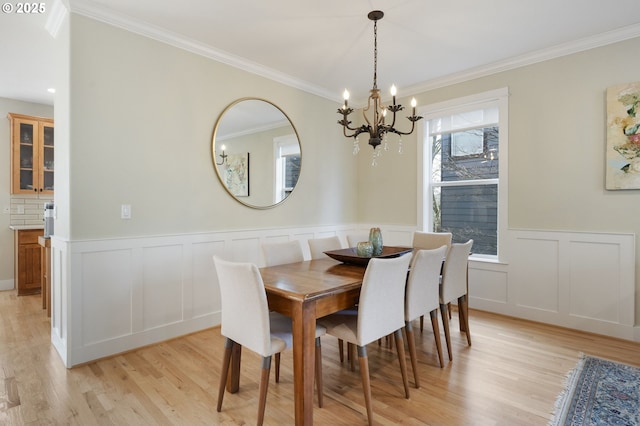 dining room with crown molding, an inviting chandelier, and light hardwood / wood-style flooring