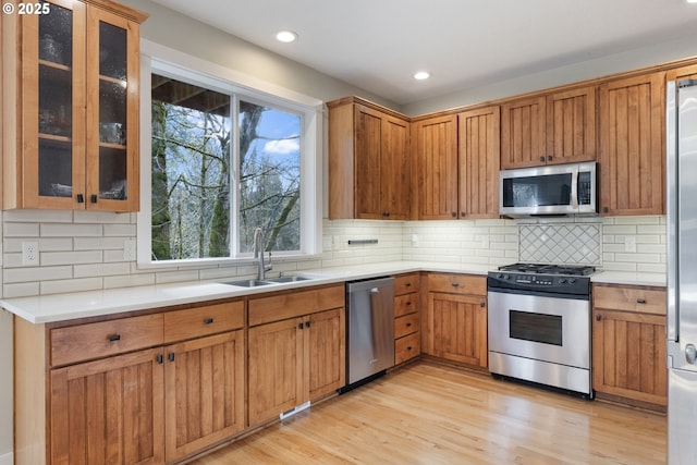 kitchen featuring appliances with stainless steel finishes, light hardwood / wood-style flooring, sink, and tasteful backsplash