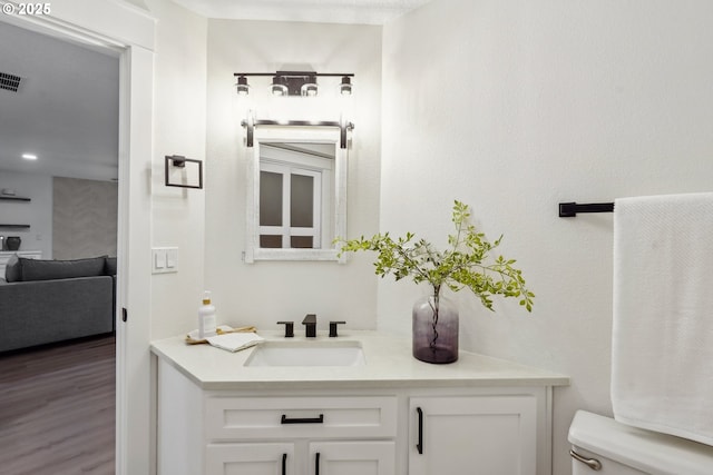 bathroom with visible vents, toilet, vanity, and wood finished floors