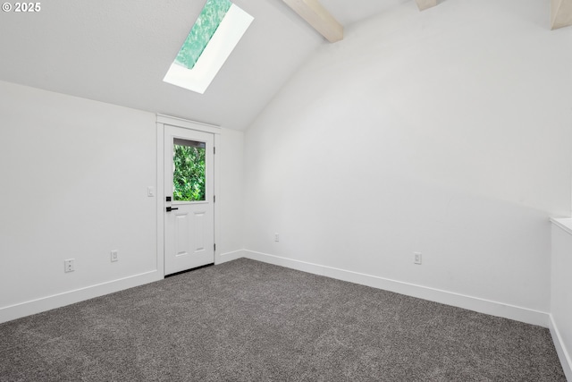 spare room with lofted ceiling with skylight, dark carpet, and baseboards