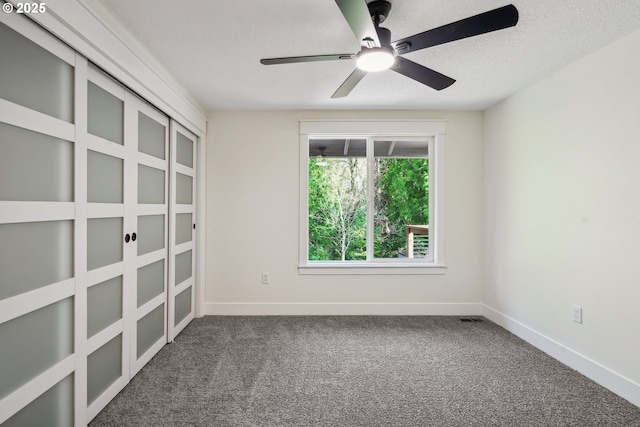 unfurnished room with carpet, a textured ceiling, baseboards, and a ceiling fan