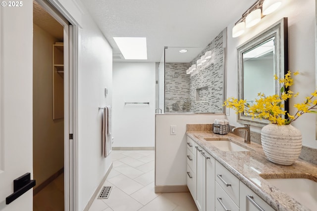 full bathroom with double vanity, a skylight, visible vents, walk in shower, and a sink