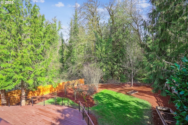 deck featuring a wooded view and a lawn