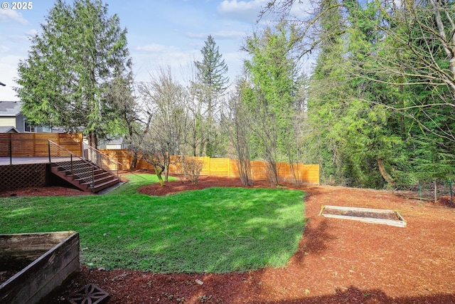 view of yard with a vegetable garden, fence, stairway, and a wooden deck