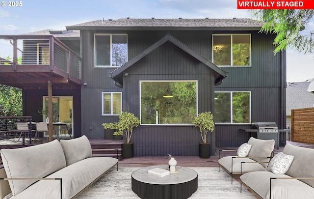 back of house with a deck, a shingled roof, and an outdoor hangout area