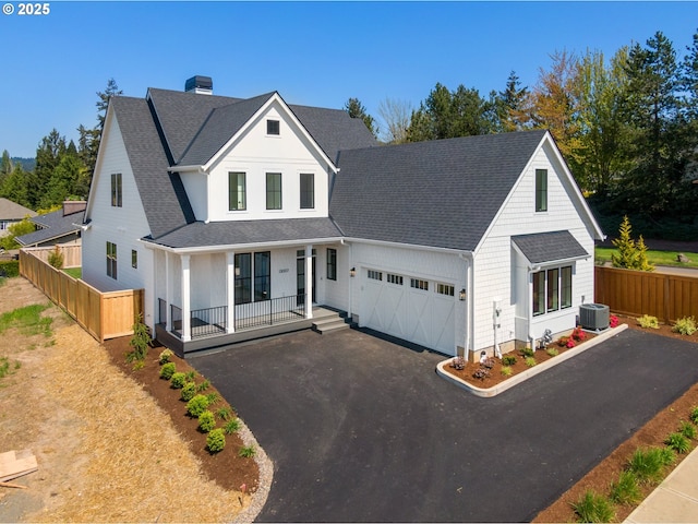 view of front facade with a porch, fence, driveway, cooling unit, and an attached garage