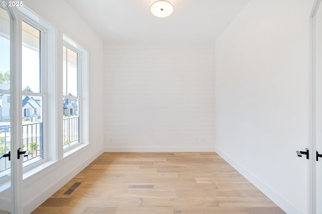spare room featuring baseboards, visible vents, light wood-style floors, and french doors