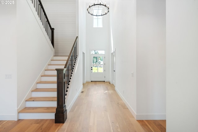entryway with baseboards, an inviting chandelier, stairs, and a towering ceiling