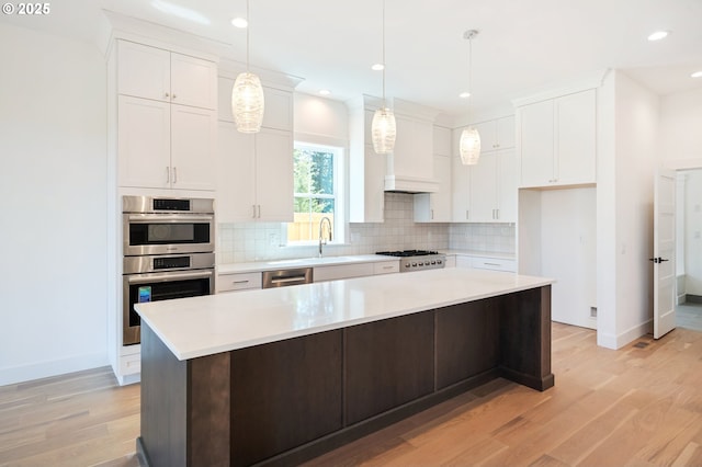 kitchen featuring stainless steel appliances, backsplash, light wood-style flooring, light countertops, and white cabinets
