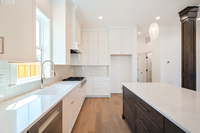 kitchen with tasteful backsplash, white cabinets, appliances with stainless steel finishes, and light wood finished floors