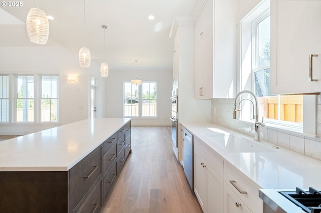 kitchen featuring white cabinets, light wood-style flooring, a sink, light countertops, and dishwashing machine