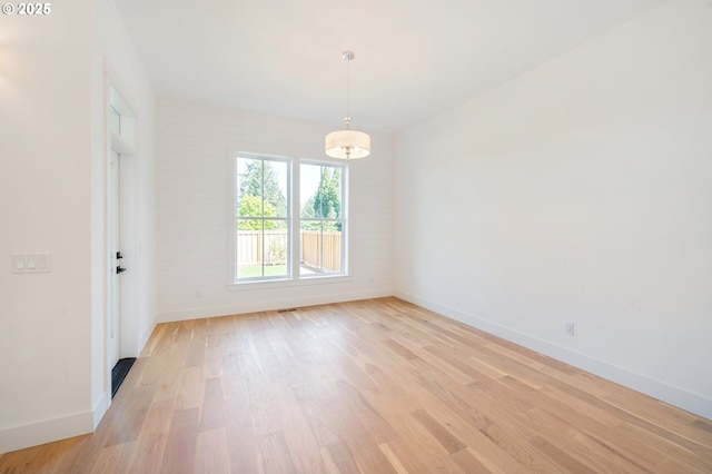 unfurnished room featuring baseboards and light wood-type flooring