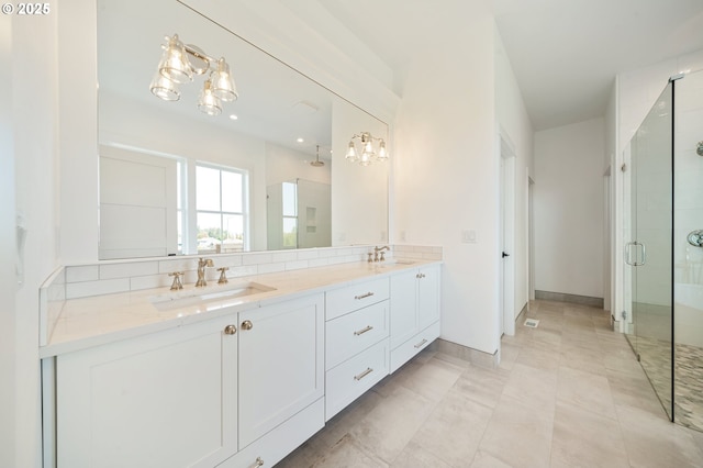 full bathroom with a stall shower, double vanity, a sink, and a chandelier