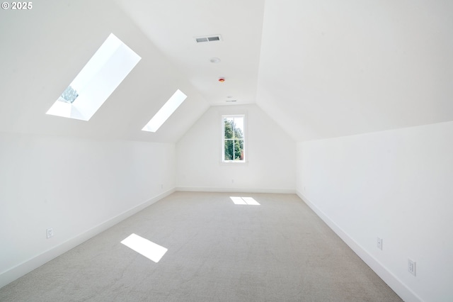bonus room featuring lofted ceiling with skylight, visible vents, baseboards, and light carpet
