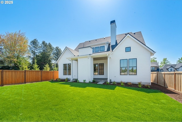 rear view of property featuring a yard, a shingled roof, a fenced backyard, and a chimney