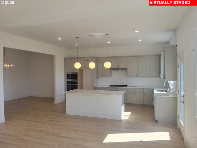 kitchen featuring gray cabinetry, appliances with stainless steel finishes, light wood-style floors, a sink, and under cabinet range hood