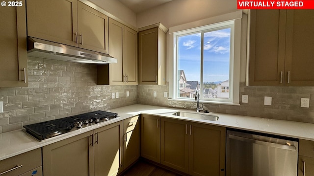 kitchen with stainless steel appliances, a sink, decorative backsplash, light countertops, and under cabinet range hood