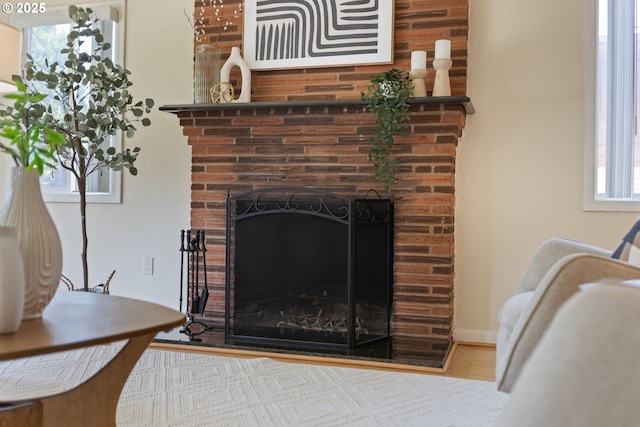 detailed view of a fireplace, wood finished floors, and baseboards