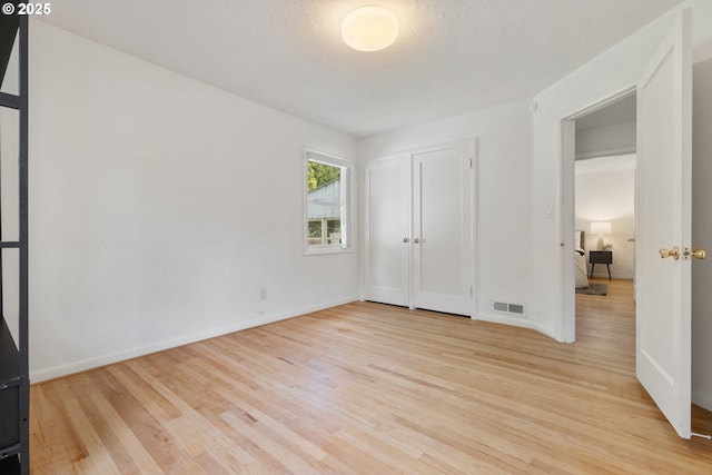 unfurnished bedroom featuring wood finished floors, baseboards, and a closet
