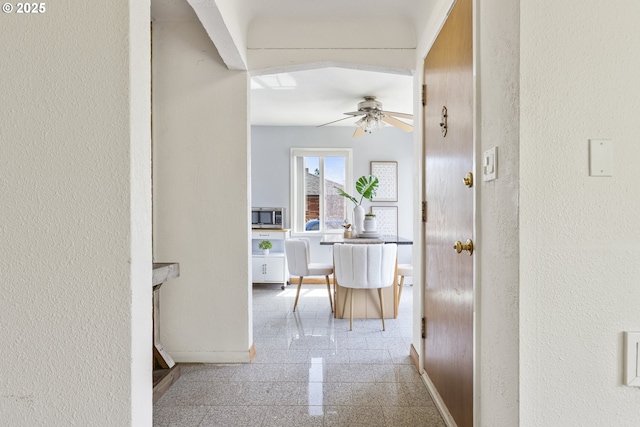 hall with granite floors, baseboards, and a textured wall