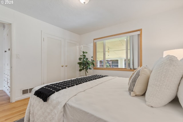 bedroom with wood finished floors, a closet, and baseboards