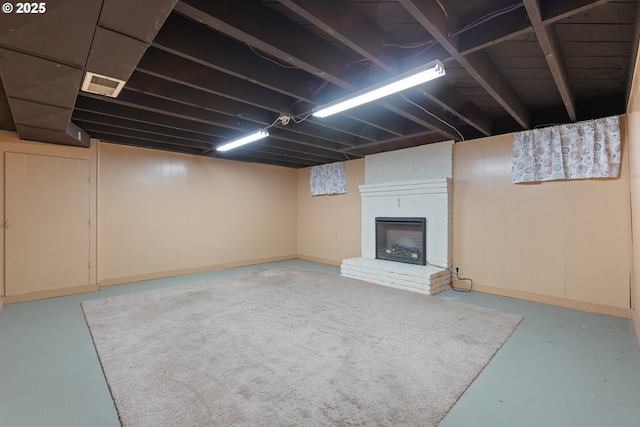 finished basement featuring a brick fireplace