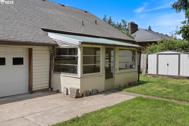 rear view of property featuring roof with shingles, a storage unit, a yard, and a garage