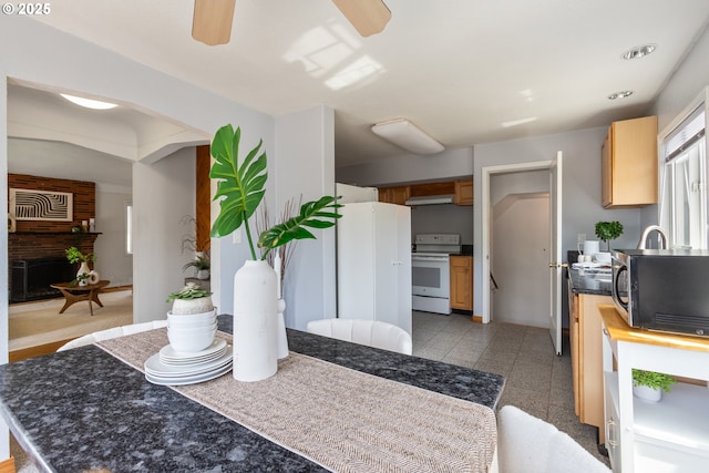 kitchen with white appliances, a ceiling fan, light brown cabinetry, and dark countertops