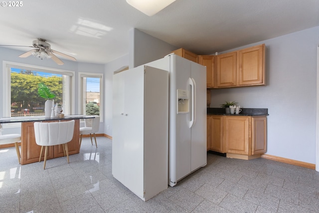 kitchen with granite tiled floors, baseboards, a ceiling fan, and dark countertops