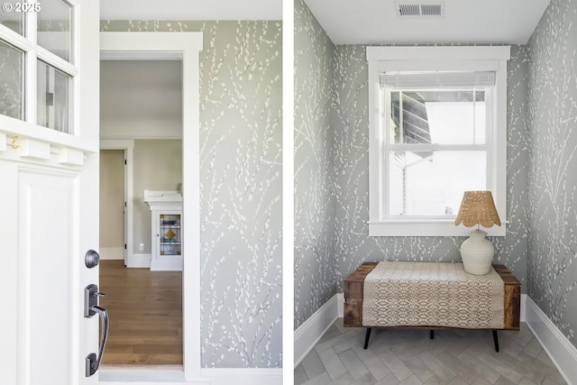 living area featuring visible vents, wallpapered walls, and baseboards