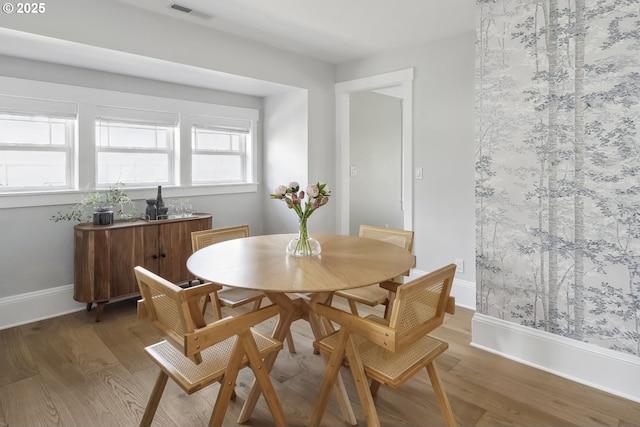 dining room featuring visible vents, baseboards, and light wood finished floors