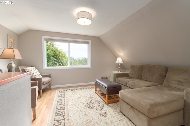 living area with vaulted ceiling, light wood-type flooring, and baseboards