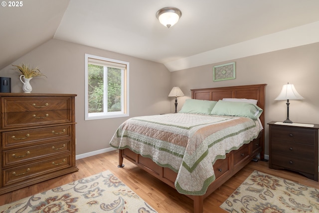 bedroom featuring vaulted ceiling, light wood-style floors, and baseboards