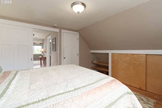 bedroom featuring wood finished floors and lofted ceiling